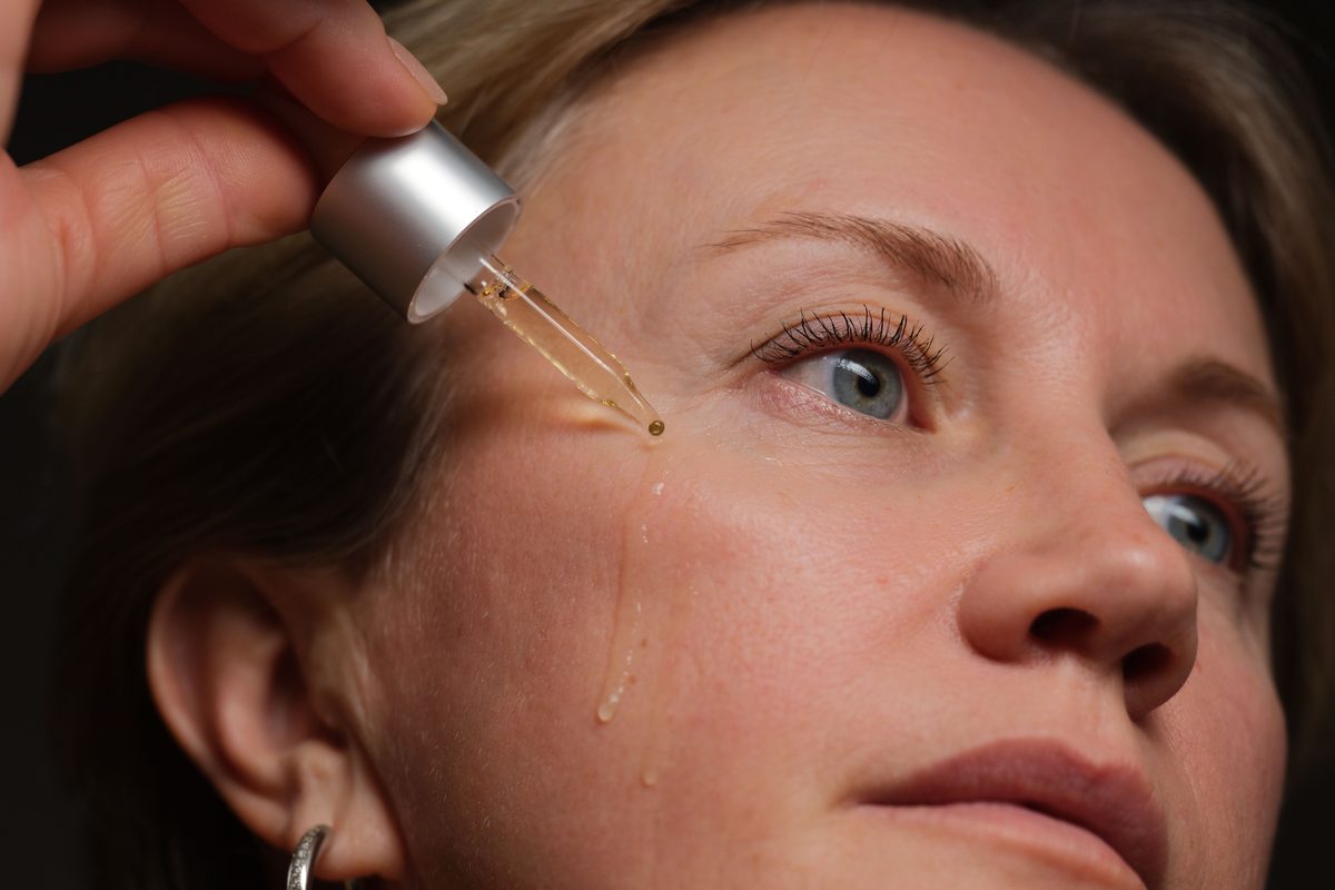 Serum dropper applying product to clear facial skin closeup — Korean skin booster guide